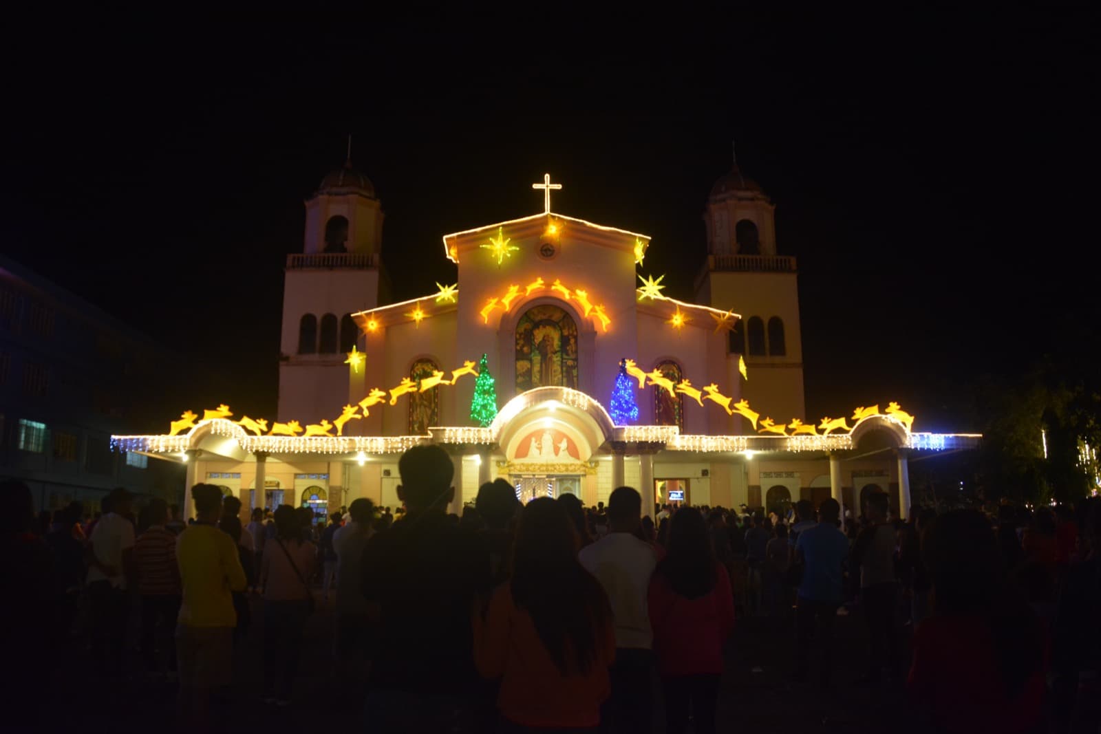 A Filipino church illuminated with Christmas lights and parol star lanterns during Simbang Gabi