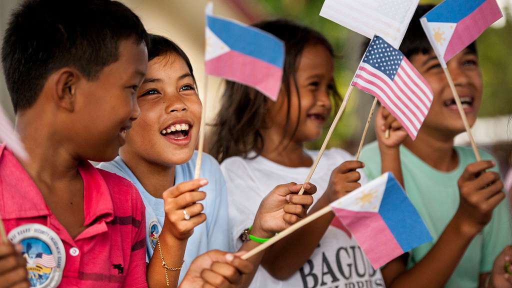 Filipino children waving Philippine and American flags